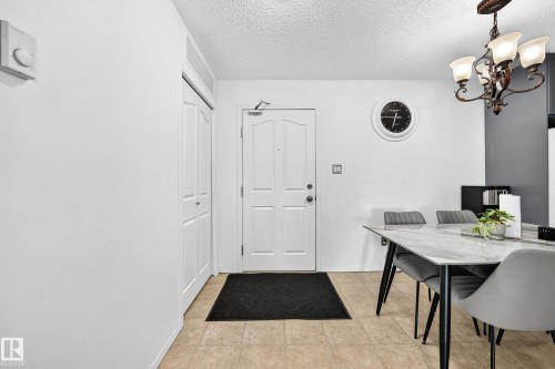 Entryway with a paneled door, built-in closet with bi-fold doors, and beige tile flooring - #133 16311 95 St Nw, Edmonton, AB 