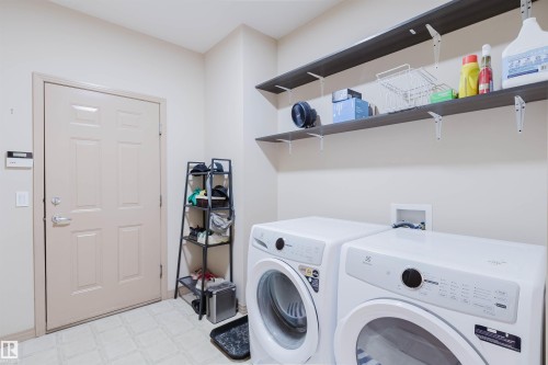Dedicated laundry area featuring a full-sized washer and dryer, integrated shelving, and a panel door - 2236 Garnett Court Nw, Edmonton, AB 