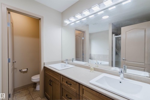 Dual vanity with integrated sinks, wood-finish cabinetry, and a full-width mirror - 2236 Garnett Court Nw, Edmonton, AB 