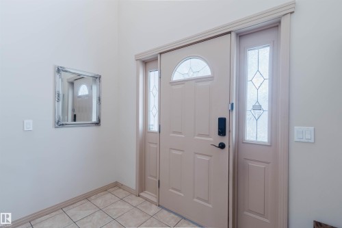 Entryway featuring a paneled door with an arched transom, sidelight with leaded glass, and tile flooring - 2236 Garnett Court Nw, Edmonton, AB 
