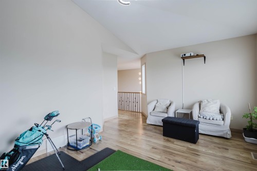 Vaulted ceiling, wood-finish flooring, half-wall with wooden handrail and metal balusters, wall-mounted shelf - 2236 Garnett Court Nw, Edmonton, AB 