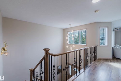 Staircase with wood newel posts, black wrought iron balusters, and wood-finish flooring - 2236 Garnett Court Nw, Edmonton, AB 