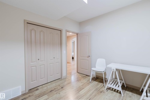 Light wood-finish flooring with neutral wall paint, bi-fold closet doors, and a paneled interior door - 2236 Garnett Court Nw, Edmonton, AB 
