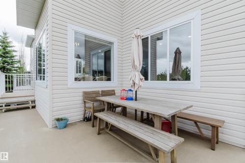 Exterior featuring horizontal siding, white-trimmed windows, a concrete patio, and a white-railed deck with steps - 2236 Garnett Court Nw, Edmonton, AB 