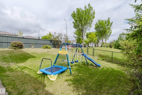 Expansive grassy area with a chain-link fence, mature trees, and shrubs - 2236 Garnett Court Nw, Edmonton, AB 