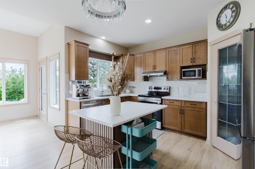 Kitchen featuring wood-finish cabinetry, stainless steel appliances, a white quartz countertop, and a tiled backsplash - 2236 Garnett Court Nw, Edmonton, AB 