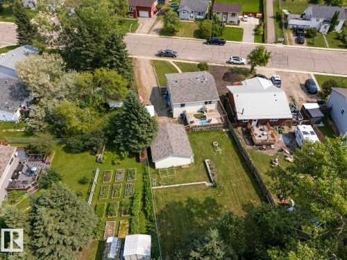 Expansive backyard featuring multiple raised garden beds, a detached shed, and mature trees - 1801 Forest Drive, Cold Lake, AB - Outdoor With View