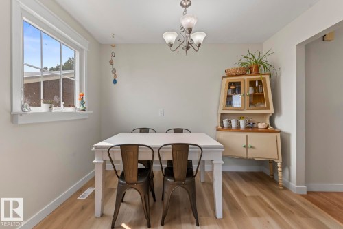 Dining area featuring wood-finish flooring, a contemporary chandelier, and a large multi-pane window with white trim - 1801 Forest Drive, Cold Lake, AB - Indoor Photo Showing Dining Room