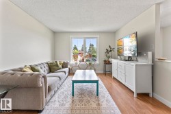 Open-concept living area featuring light-toned walls and wood-finish flooring - 