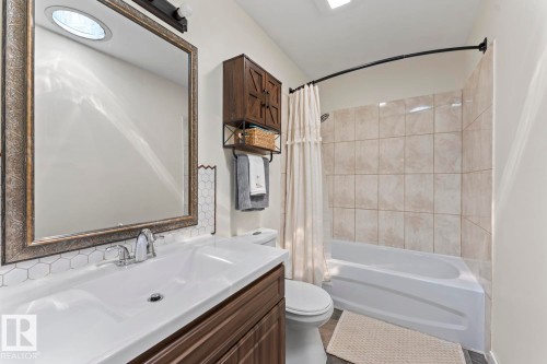 Bathroom vanity featuring an integrated sink, chrome faucet, and decorative framed mirror - 1801 Forest Drive, Cold Lake, AB - Indoor Photo Showing Bathroom