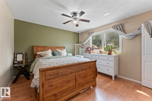 Spacious room featuring wood-finish flooring, a ceiling fan with integrated lighting, and a large window providing natural illumination - 1801 Forest Drive, Cold Lake, AB - Indoor Photo Showing Bedroom