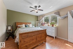 Spacious room featuring wood-finish flooring, a ceiling fan with integrated lighting, and a large window providing natural illumination - 