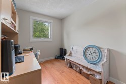 Light-filled room featuring a built-in desk with integrated shelving, wood-finish flooring, and a window with white trim - 