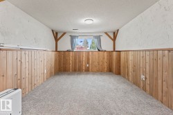 Finished room featuring wood-panel wainscoting, textured white walls, and a window providing natural light - 