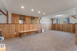 Spacious room featuring wood paneling, light-colored carpeting, and recessed lighting - 