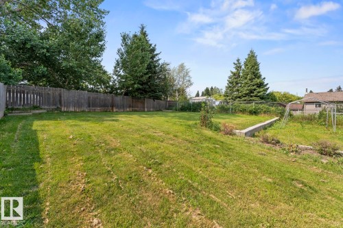 Expansive green space featuring a wood fence perimeter and mature trees - 1801 Forest Drive, Cold Lake, AB - Outdoor