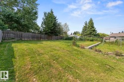 Expansive green space featuring a wood fence perimeter and mature trees - 