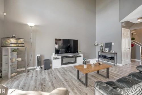 Vaulted ceiling, light-toned wood-finish flooring, neutral wall paint, white trim, and a built-in entertainment unit - #13 6608 158 Av Nw, Edmonton, AB 