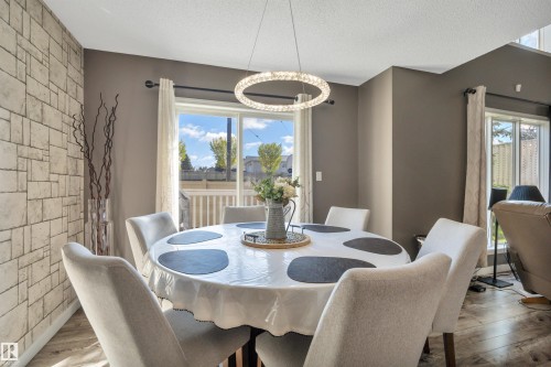 Contemporary chandelier lighting, durable wood-finish flooring, and a sliding glass door with exterior access - #13 6608 158 Av Nw, Edmonton, AB 