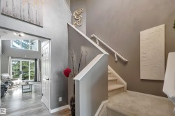 Carpeted staircase with white handrail, leading to an arched entryway with wood-finish flooring - 