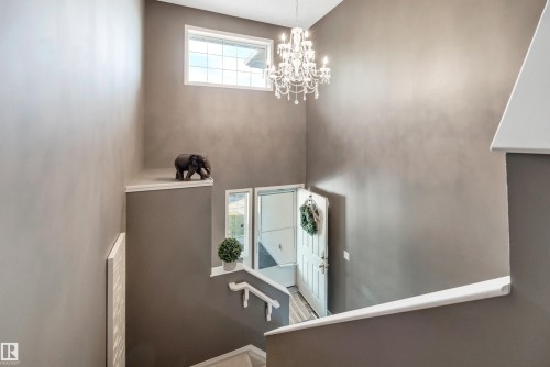Foyer with a prominent staircase, high ceilings, large transom window, and a chandelier - #13 6608 158 Av Nw, Edmonton, AB 
