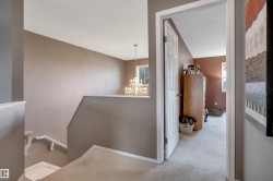 Carpeted flooring, white trim details, an interior doorway, and a chandelier with multiple light sources - 