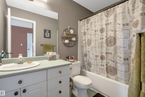 White vanity with multiple drawers and cabinet storage, integrated white sink, and a large wall-mounted mirror - #13 6608 158 Av Nw, Edmonton, AB 