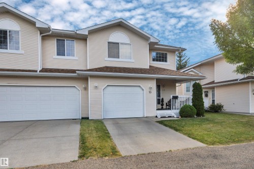 Exterior featuring light-colored siding, multiple gables, and an attached two-car garage - #13 6608 158 Av Nw, Edmonton, AB 