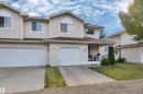 Exterior featuring light-colored siding, multiple gables, and an attached two-car garage - #13 6608 158 Av Nw, Edmonton, AB 