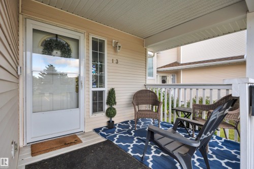 Covered front porch with white railings and vinyl siding - #13 6608 158 Av Nw, Edmonton, AB 