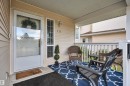 Covered front porch with white railings and vinyl siding - #13 6608 158 Av Nw, Edmonton, AB 
