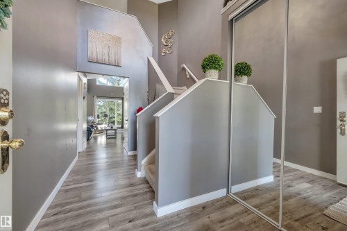 Vaulted ceilings, wood-finish flooring, staircase with carpeted treads, mirrored closet doors, and contemporary wall decor - #13 6608 158 Av Nw, Edmonton, AB 
