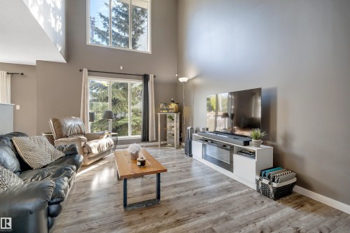 Vaulted ceiling, large picture windows, wood-finish flooring, and neutral wall tones - #13 6608 158 Av Nw, Edmonton, AB 