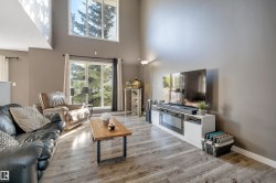 Vaulted ceiling, large picture windows, wood-finish flooring, and neutral wall tones - 