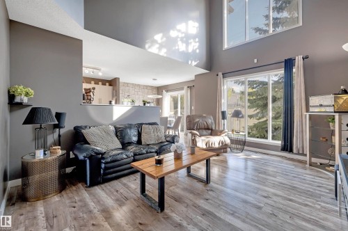 Expansive living area with wood-finish flooring, high ceilings, and large windows - #13 6608 158 Av Nw, Edmonton, AB 