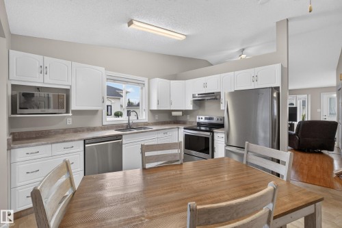 White cabinetry, stainless steel appliances, built-in microwave, and wood-finish flooring - 365 Hollick-Kenyon Road Nw, Edmonton, AB 