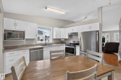 White cabinetry, stainless steel appliances, built-in microwave, and wood-finish flooring - 
