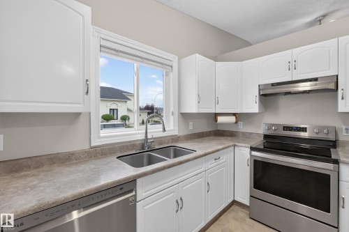 White cabinetry, dual basin stainless steel sink, stainless steel dishwasher, stainless steel range, and a coordinating range hood - 365 Hollick-Kenyon Road Nw, Edmonton, AB 