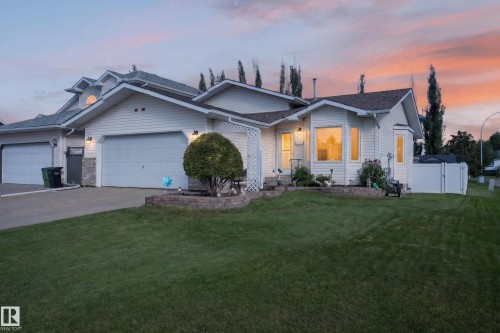 Expansive front lawn, two-car garage, white vinyl siding, bay window, and a white privacy fence - 365 Hollick-Kenyon Road Nw, Edmonton, AB 