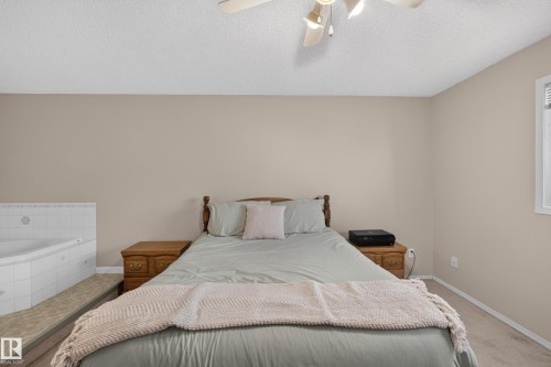Built-in jetted tub with white tile surround, ceiling fan with integrated lighting, and a window with blinds - 365 Hollick-Kenyon Road Nw, Edmonton, AB 