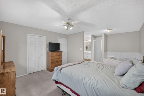 Recessed jetted tub with tiled surround, separate shower with glass enclosure, single vanity with integrated sink, and ceiling fan with lighting - 365 Hollick-Kenyon Road Nw, Edmonton, AB 