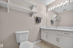 White vanity with integrated sink, full-width mirror, and overhead vanity lighting - 