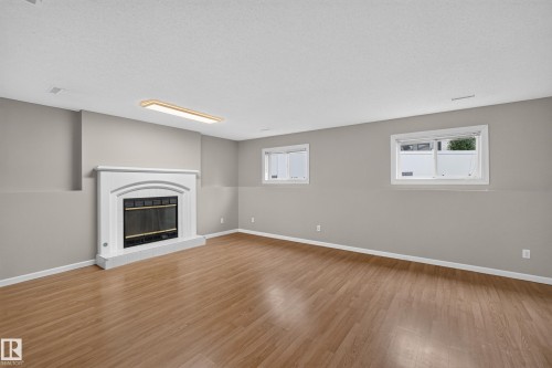 Wood-finish flooring, white fireplace with hearth, and two windows - 365 Hollick-Kenyon Road Nw, Edmonton, AB 