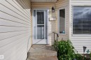 Light-toned siding exterior featuring a storm door, concrete entry stairs, and a bay window - 365 Hollick-Kenyon Road Nw, Edmonton, AB 