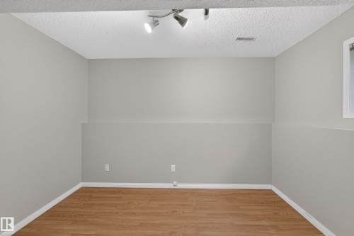 Wood-finish flooring, neutral wall paint, textured ceiling, track lighting, and a window with white trim - 365 Hollick-Kenyon Road Nw, Edmonton, AB 