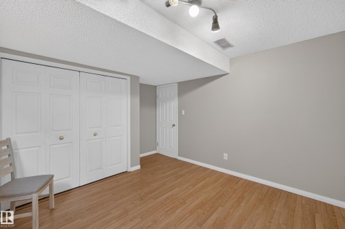 Wood-finish flooring with light gray wall paint, featuring a wide closet with bi-fold doors - 365 Hollick-Kenyon Road Nw, Edmonton, AB 