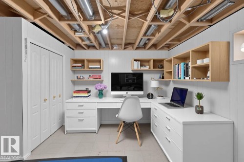 White paneled walls with exposed ceiling joists, white desk with storage drawers, light wood-finish wall-mounted shelving, and bi-fold closet doors - 365 Hollick-Kenyon Road Nw, Edmonton, AB 