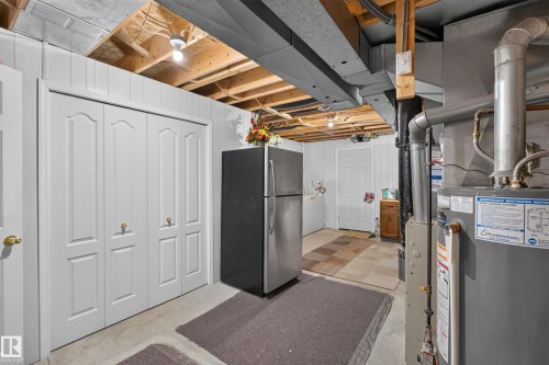 Utility area with exposed ceiling joists, white paneled walls, and a water heater installation - 365 Hollick-Kenyon Road Nw, Edmonton, AB 