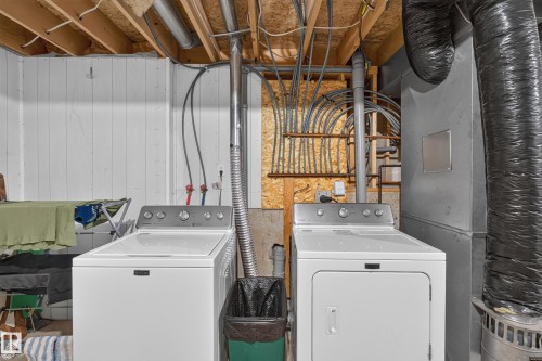 Laundry area featuring a top-load washer, front-load dryer, exposed ceiling joists, and visible utility lines - 365 Hollick-Kenyon Road Nw, Edmonton, AB 