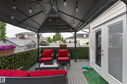 Covered outdoor deck with grey composite decking, framed by a decorative green privacy screen - 365 Hollick-Kenyon Road Nw, Edmonton, AB 